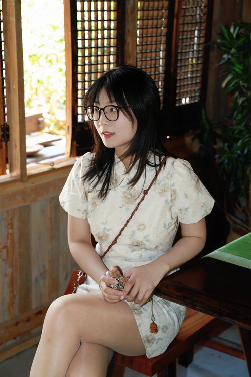 Free A young woman sits indoors in Hefei, China, wearing a traditional Chinese dress and glasses. Stock Photo