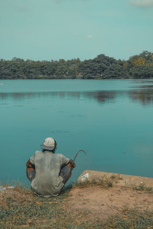 Free A lone man sits by a tranquil river in Wennappuwa, Sri Lanka, lost in thought. Stock Photo