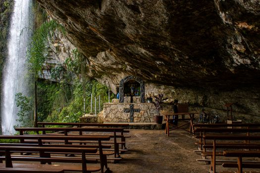 A serene cave altar setup with waterfall backdrop in Alfredo Wagner, Brazil.