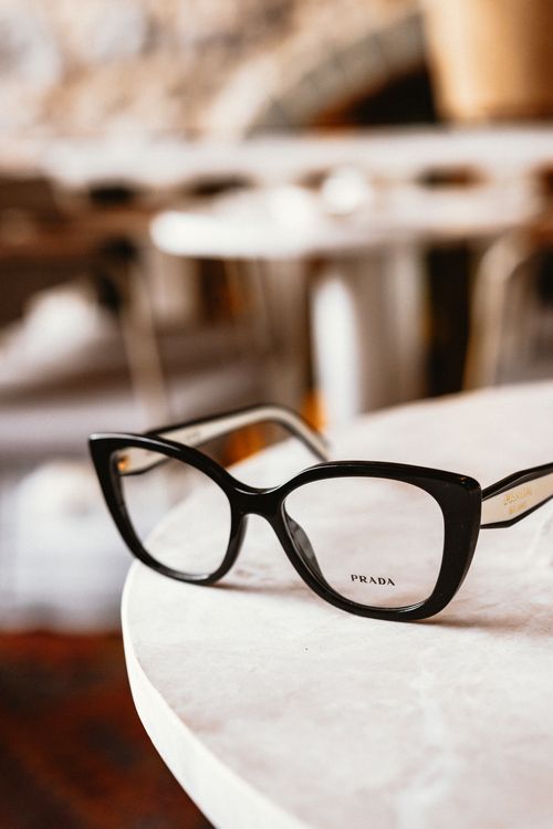 Free Elegant black cat eye glasses resting on a marble table in a cozy indoor setting. Stock Photo