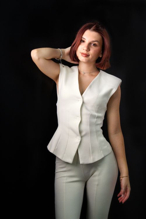 Free Stylish woman posing in a white outfit on a dark background, showcasing elegance and modern fashion. Stock Photo