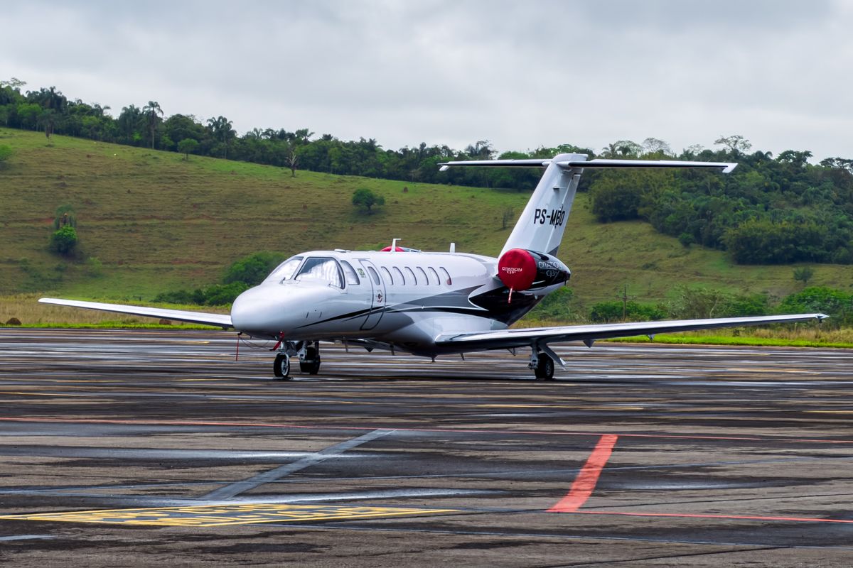 A small business jet parked on the apron with green hills behind, typical of the light side of a light jet vs midsize jet comparison
