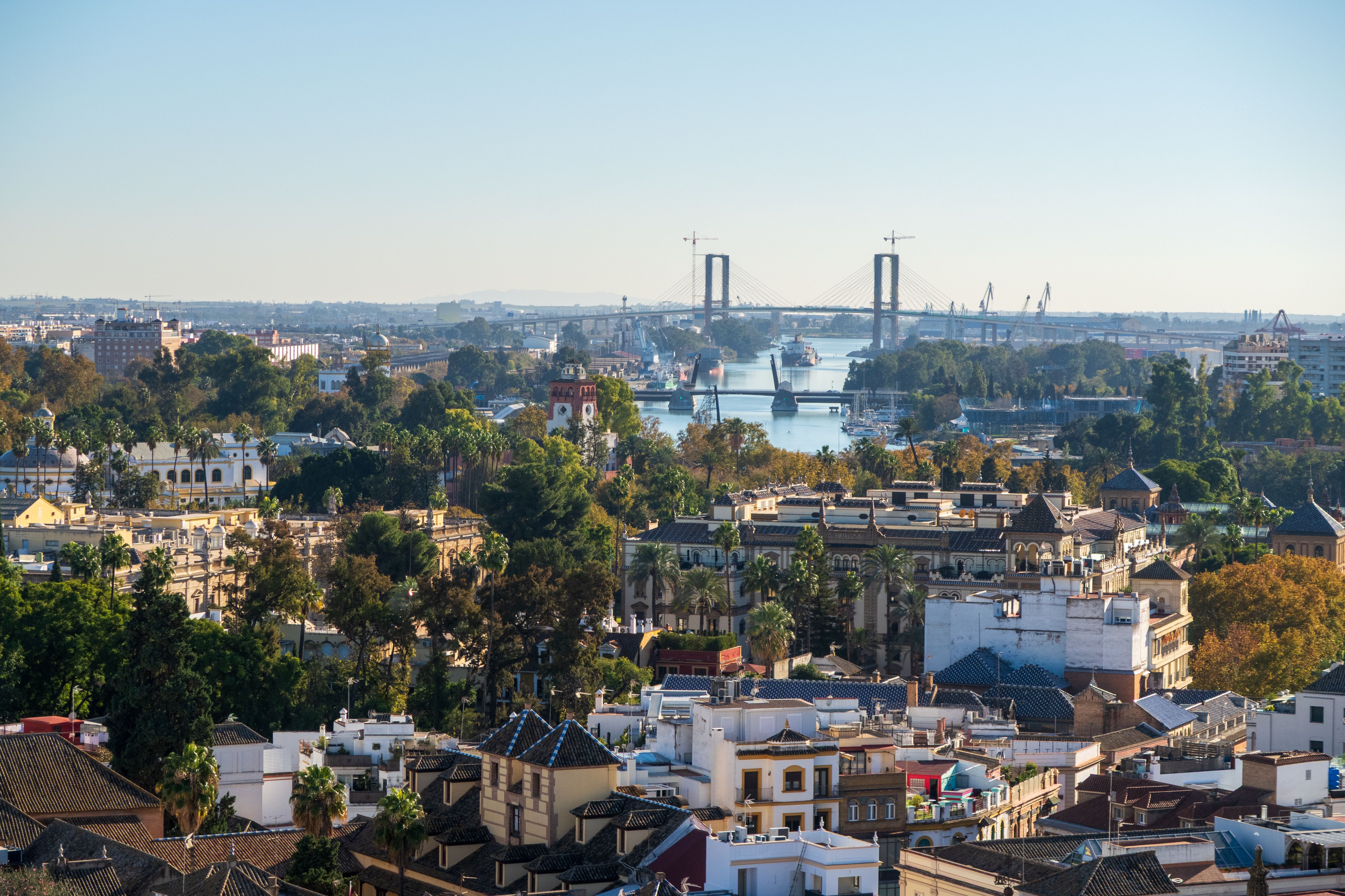 A scenic aerial view of Seville, Spain, showcasing the Isabel II Bridge and cityscape.