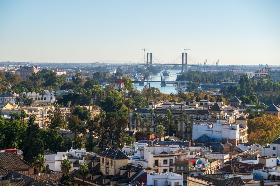 A scenic aerial view of Seville, Spain, showcasing the Isabel II Bridge and cityscape.