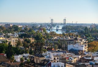 A scenic aerial view of Seville, Spain, showcasing the Isabel II Bridge and cityscape.
