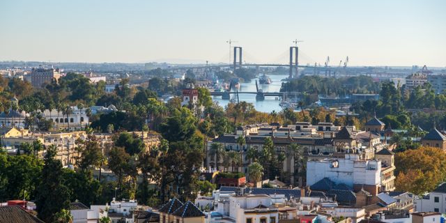 A scenic aerial view of Seville, Spain, showcasing the Isabel II Bridge and cityscape.