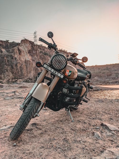 Free Old motorcycle parked on empty street near rock in countryside while sun going down Stock Photo