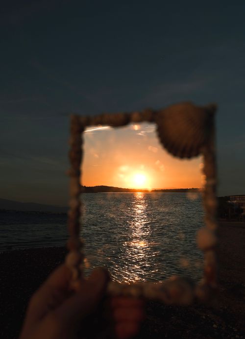 Free A sunset over the ocean framed within a seashell-decorated border, creating a stunning visual effect. Stock Photo
