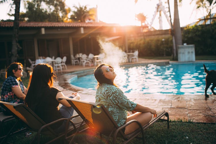 Young Woman Smoking While Resting On Poolside