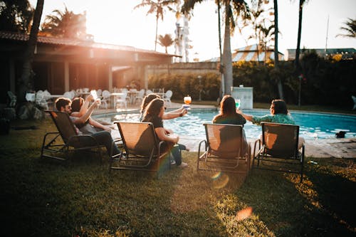 Group of friends drinking alcoholic beverages in yard of hotel