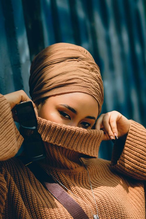 Free Stylish portrait of a woman in Abuja wearing a brown headscarf and sweater, exuding confidence outdoors. Stock Photo