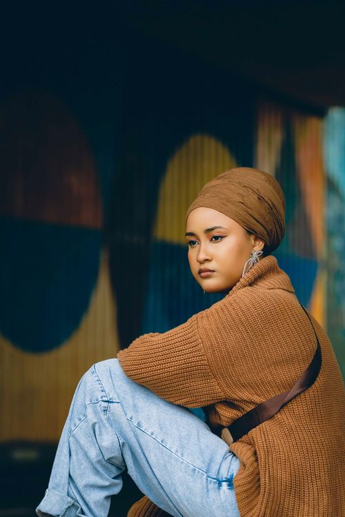 Free Portrait of a woman in cozy streetwear against a colorful abstract background in Abuja. Stock Photo