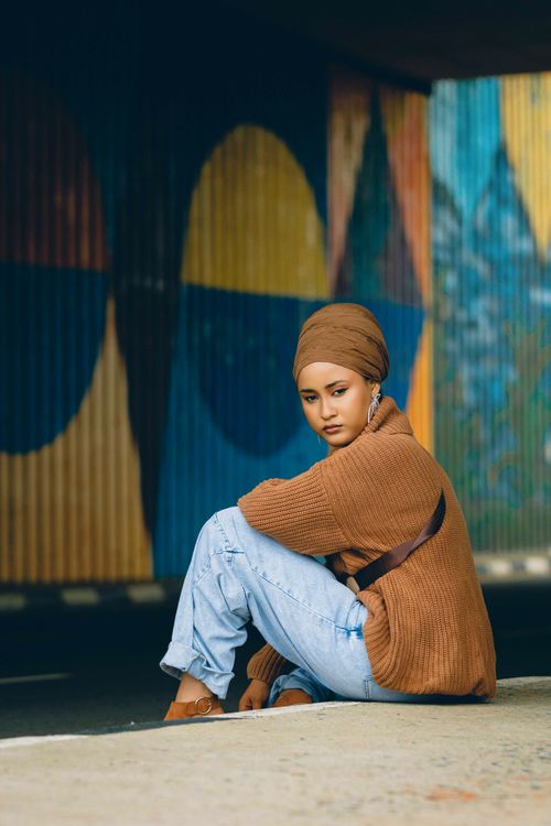 Free Creative outdoor portrait of a young woman in jeans and sweater against colorful mural. Stock Photo