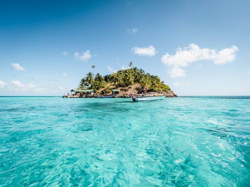 Зеленый и коричневый остров на синем море под голубым небом