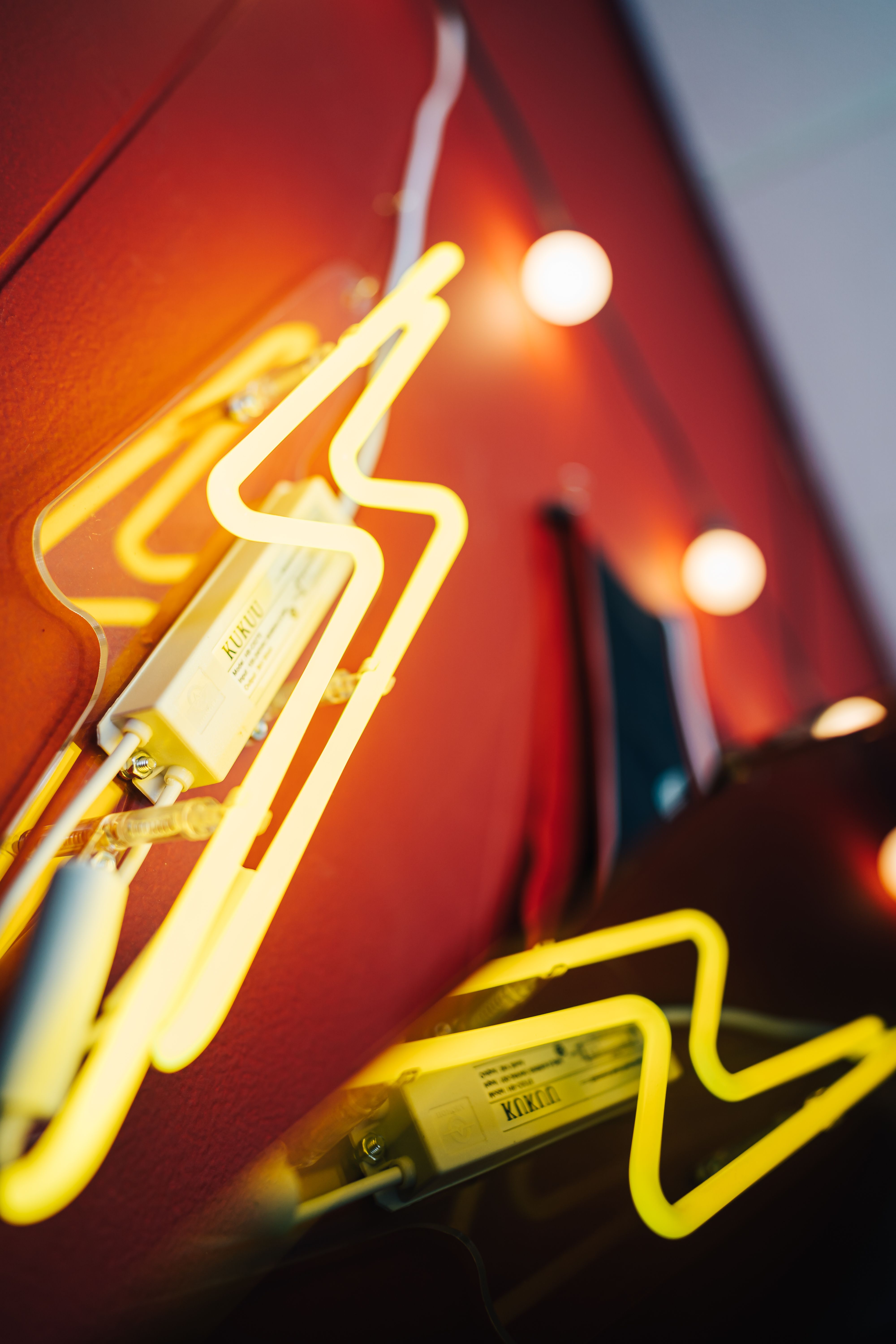 Low angle close up of yellow and white garlands attached to red wall in bright room and reflecting from metallic surface