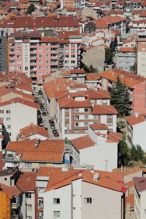 Free High-angle view of dense urban housing with red roofs under clear blue sky on a sunny day. Stock Photo