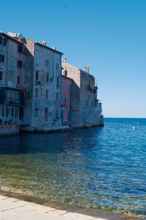 Free Rustic seaside buildings along clear Adriatic waters in bright daylight, perfect summer travel scene. Stock Photo