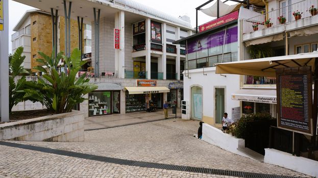 View of a commercial street with shops and modern architecture in Colares, Portugal.