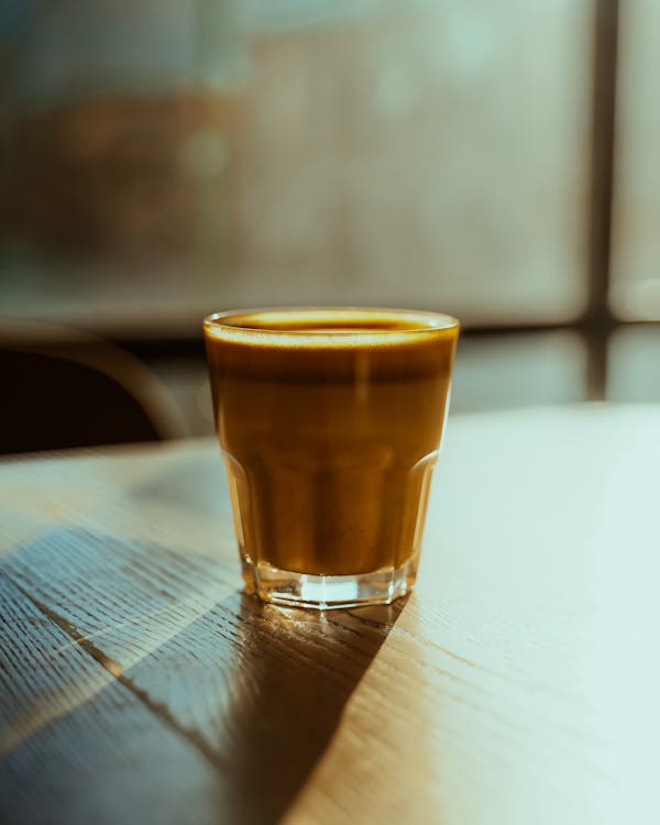 Free Clear Drinking Glass With Coffee on Brown Wooden Table Stock Photo