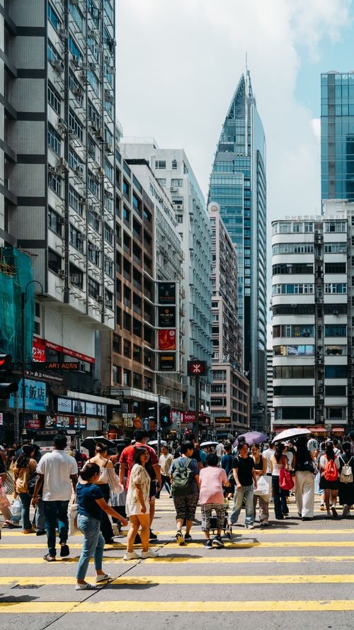 Free Crowds navigate a busy street in Hong Kong surrounded by modern skyscrapers and urban architecture. Stock Photo