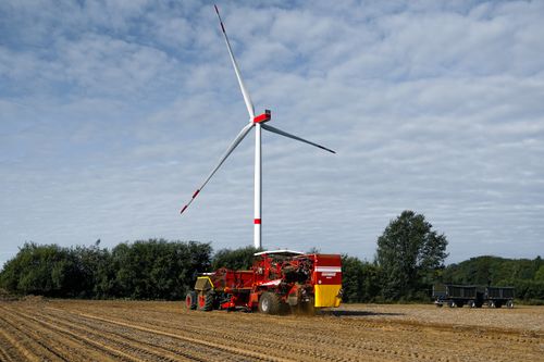 Free A farming machine in action near a wind turbine in Lütau, Germany. Stock Photo