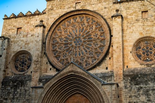 Free Historical gothic architecture featuring intricate rose windows in a monastery facade at sunset. Stock Photo