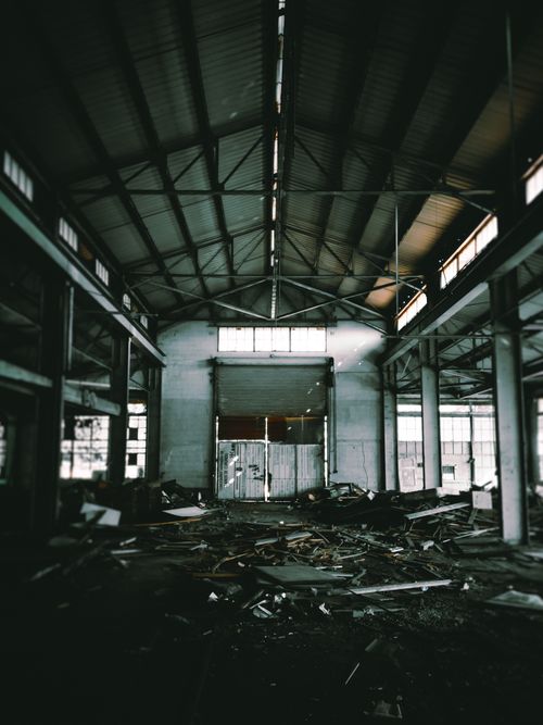 Free Huge hall of empty abandoned industrial building including trash on floor and high grey ceiling supported by columns Stock Photo