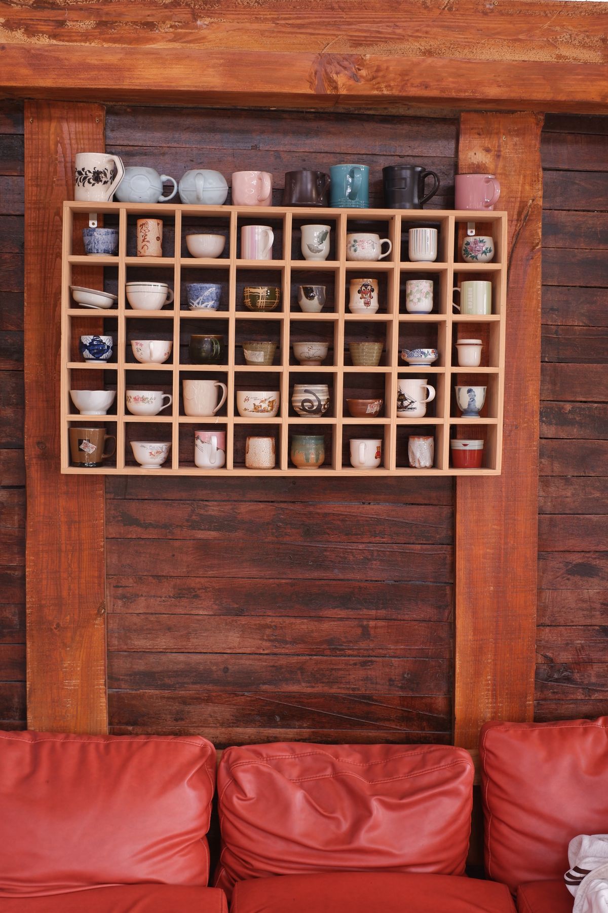 A collection of mugs displayed on a wooden shelf with a rustic background