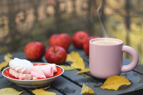 Free Cozy autumn scene with hot coffee, apples, meringue, and fallen leaves on a table. Stock Photo