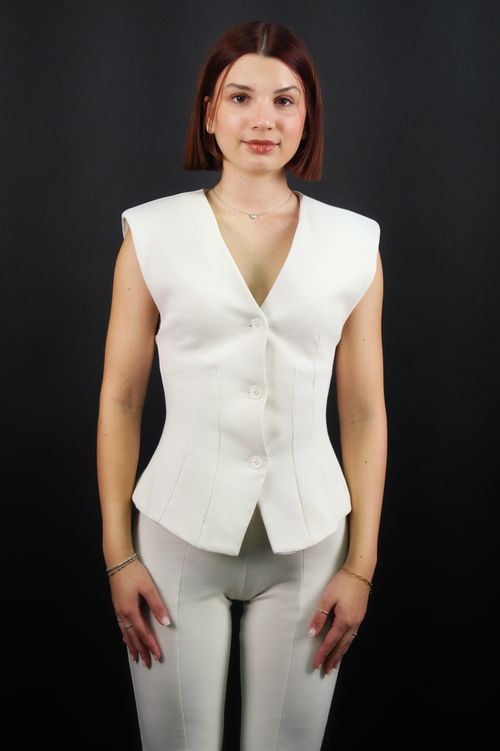 Free Young woman posing confidently in elegant white attire, featuring a sleeveless vest and pants. Stock Photo