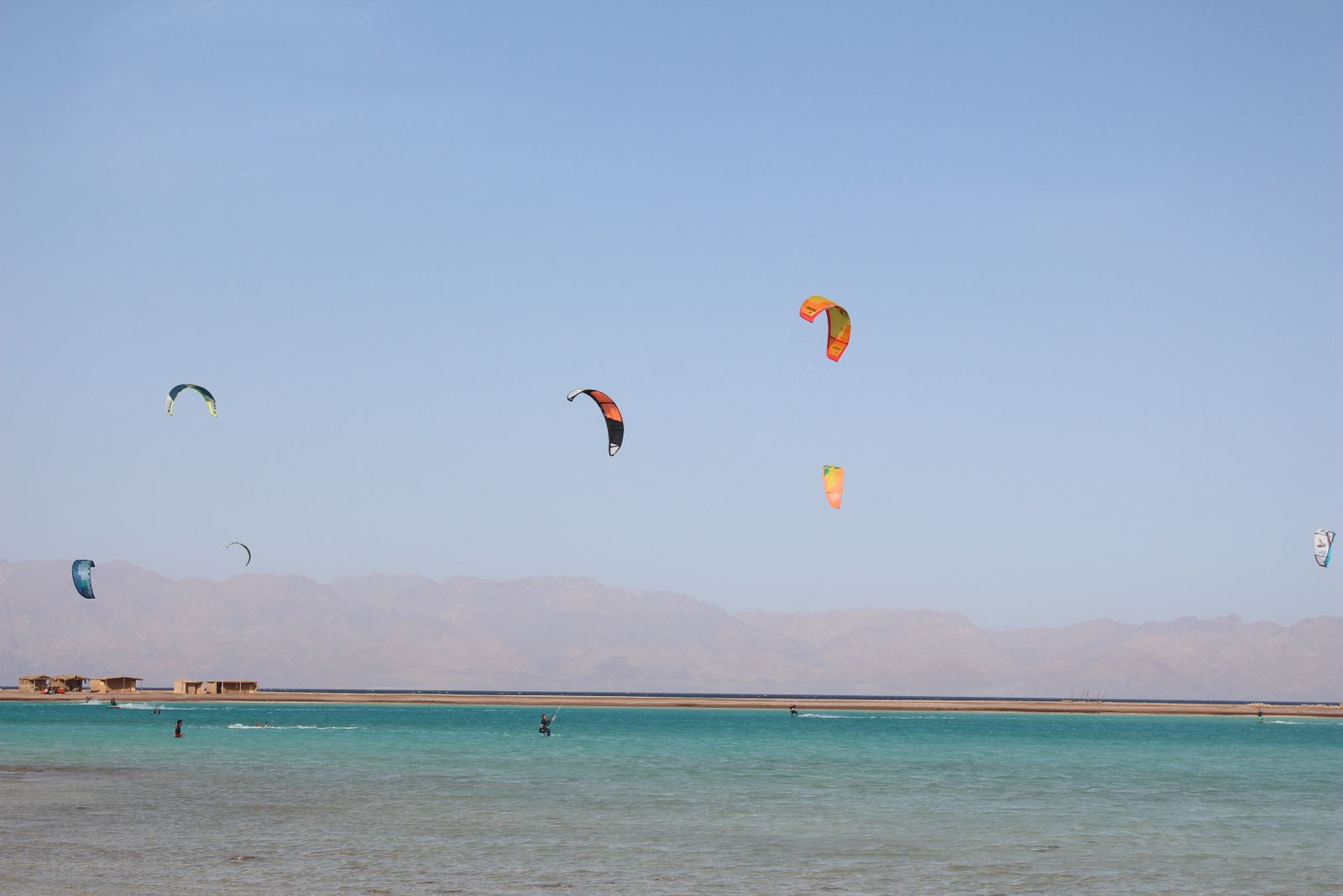 Kitesurfers gliding across clear water near Dahab, Egypt