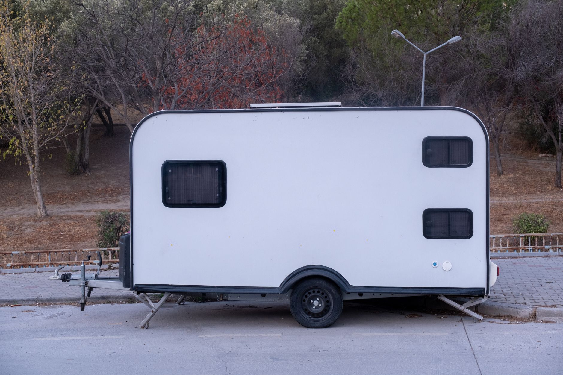 A simple white caravan parked outdoors in a natural setting in Izmir, Turkey.