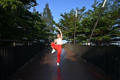 Free Woman performing yoga outdoors on a bridge surrounded by greenery in Indonesia. Stock Photo