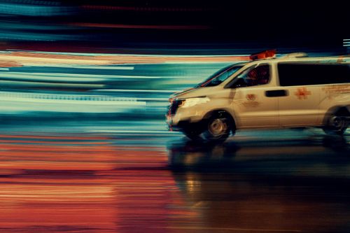 Free Blurred action shot of an ambulance speeding through rainy city streets at night. Stock Photo