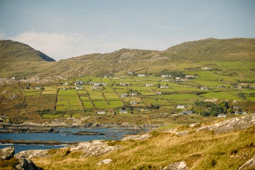 Free Beautiful landscape in Ireland featuring lush green fields and a rocky coastline under a clear sky. Stock Photo