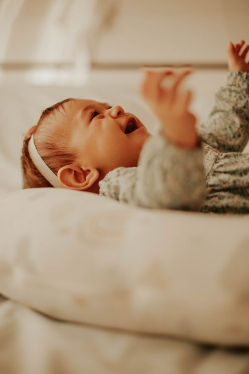 Free Charming image of a joyful baby lying indoors, expressing happiness in warm, soft tones. Stock Photo