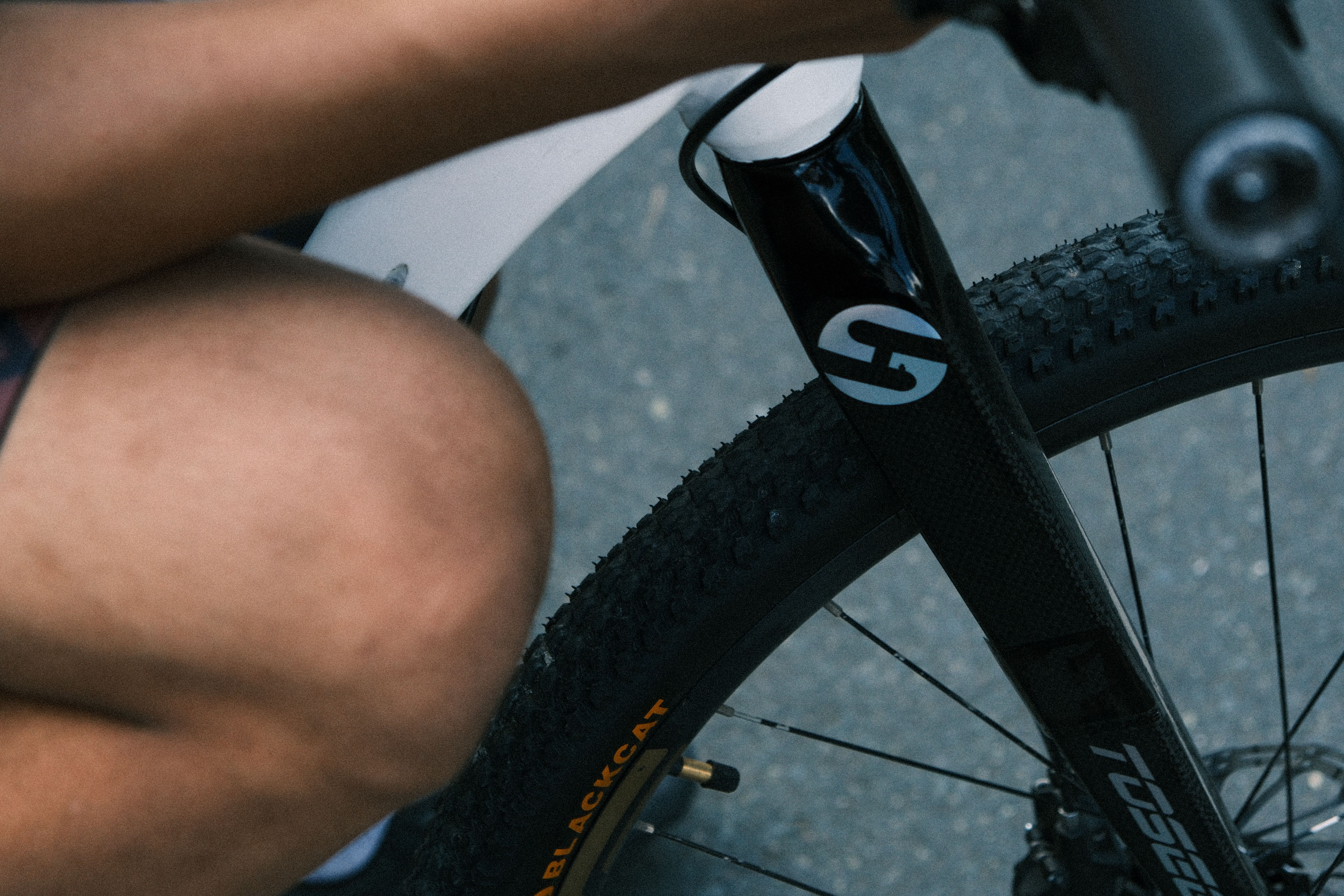 Detailed view of a cyclist's leg and mountain bike tire, showcasing outdoor activity and sports gear.