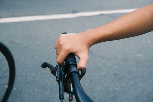 Free An adult's hand firmly grips a bicycle handlebar on a sunny day. Stock Photo