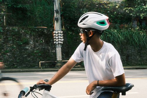 Free A young man in a helmet rides a bicycle outdoors on a sunny day. Stock Photo