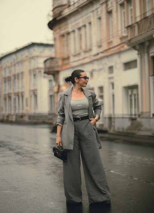 Free Chic woman wearing grey suit and sunglasses poses stylishly on a Brazilian street. Stock Photo