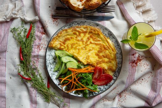 Tasty omelette served with fresh salad, chili, herbs, and a refreshing lemonade.
