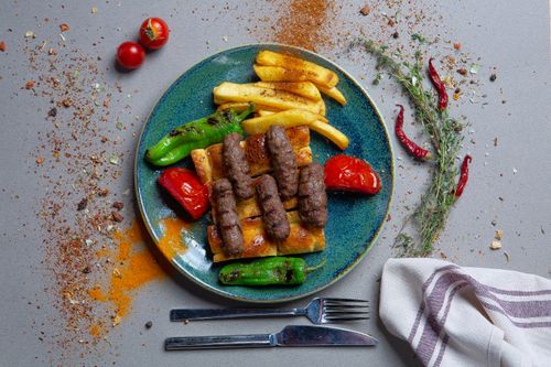 Free Plate of Mediterranean kebabs with vegetables and fries on a rustic setting. Stock Photo