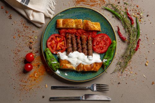 Free A plate of Turkish kebabs with bread, peppers, and tomatoes, garnished with spices. Stock Photo