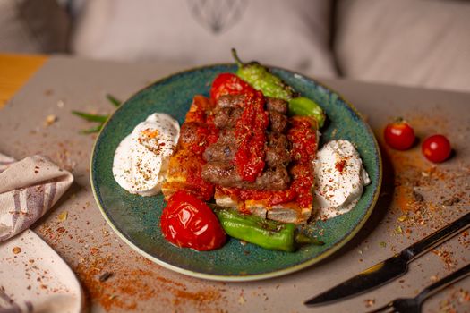 Appetizing grilled kebab served with yogurt, peppers, and tomato sauce on a plate.