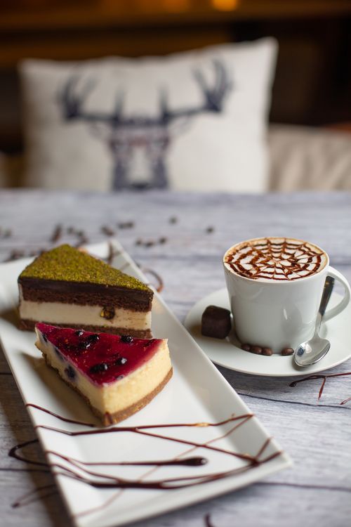 Free A delicious coffee with artistic foam and berry cheesecake on a wooden table. Stock Photo