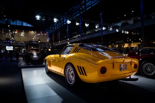 Free Vintage yellow sports car displayed at an indoor auto show with dramatic lighting and classic design. Stock Photo