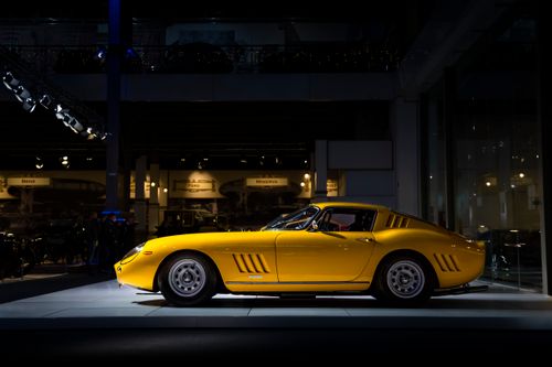 Free Profile view of a classic yellow sports car under dramatic showroom lighting, showcasing elegant design. Stock Photo
