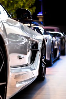 Close-up view of a row of modern sports cars at an indoor auto exhibition.