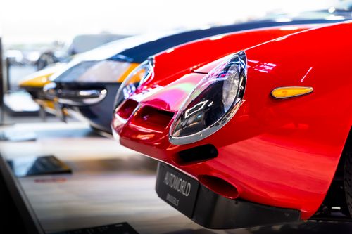 Free Close-up of a vintage red sports car's front end displayed at an auto exhibition, showcasing classic design details. Stock Photo