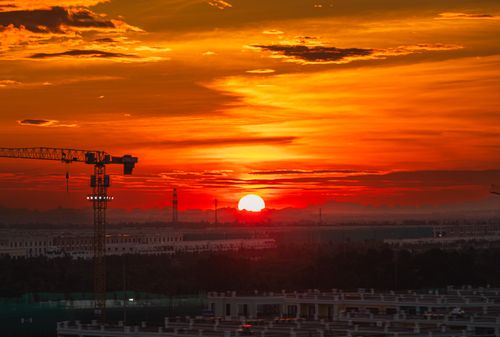 Free Vibrant sunset over Haiphong cityscape with construction cranes silhouetted against fiery skies. Stock Photo